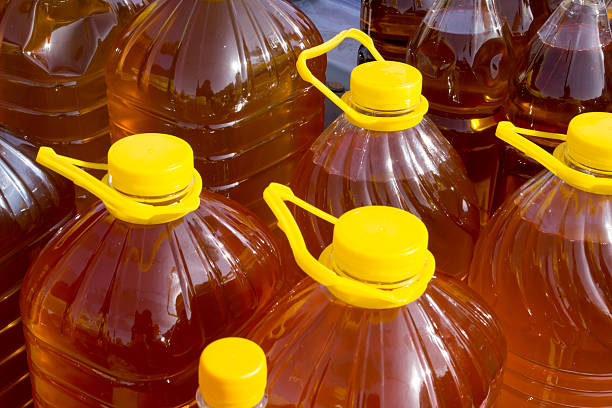 Bottles of infused olive oil with herbs and spices. Close-up of glass bottles filled with olive oil infused with rosemary, garlic, and dried chili peppers, displayed for sale