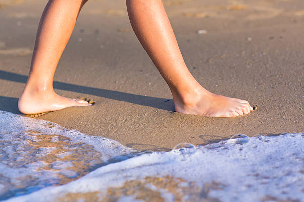 istock Child walking with bare feet along the seashore 470978977