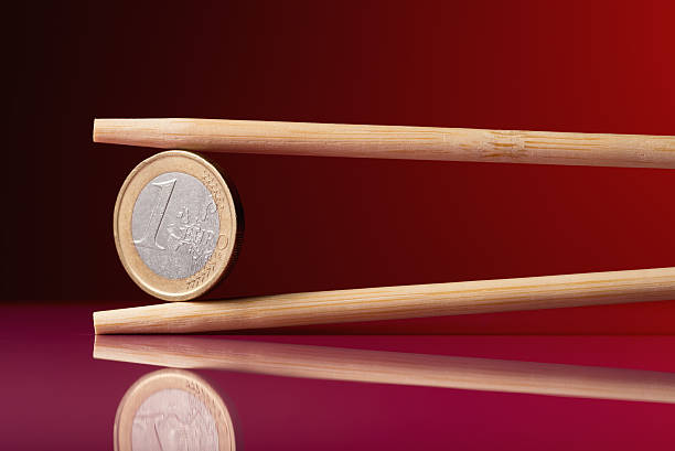 istock One euro coin and chopstick over red background 470979088