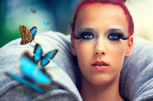 Red-haired woman with a group of Blue Morpho Butterflies (Morpho peleides) flying on her side.