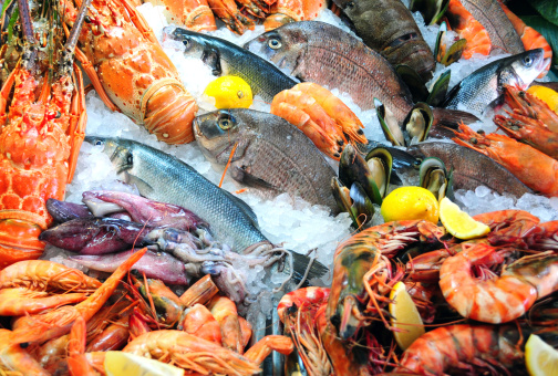 A selection of seafood in polystyrene cool boxes, being kept cold in ice at a market stall in Northumberland. There are signs in the boxes to notify the customer of what is on sale.