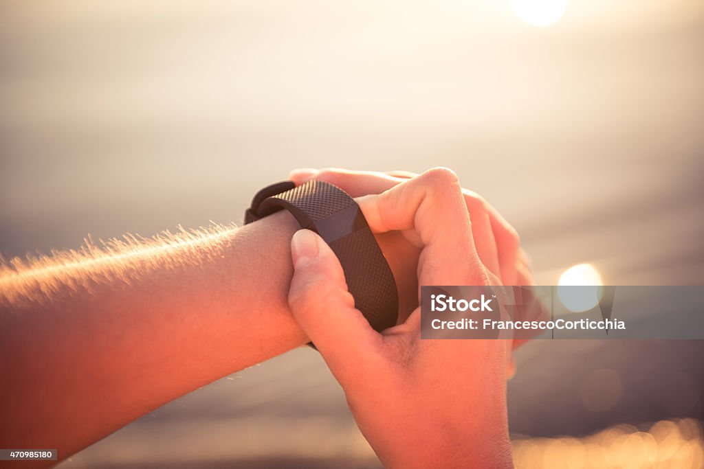 Young woman jogging with heart rate monitor Young caucasian woman watch her heart rate watch (heart rate monitor) with blank screen during jogging at the beach during the sunset. 20-29 Years Stock Photo