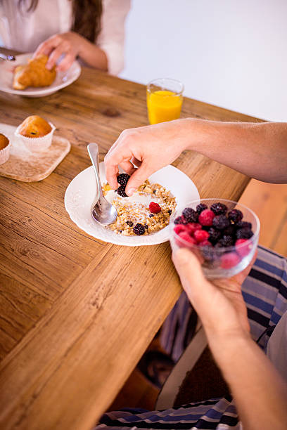 istock Man putting fresh berries into his bowl of cereal 470985686