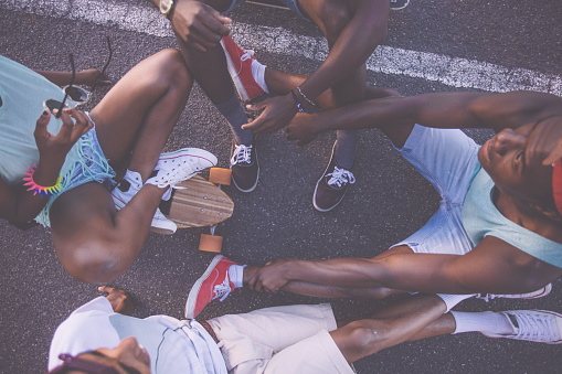 Overhead shot of  a group of skater friends sitting together in a circle on their longboards together