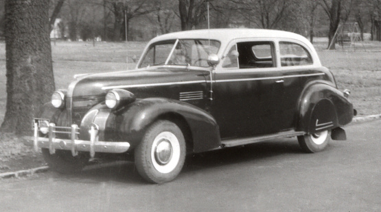 Antique General Motors two door sedan parked on the side of the street in vintage black and white photo