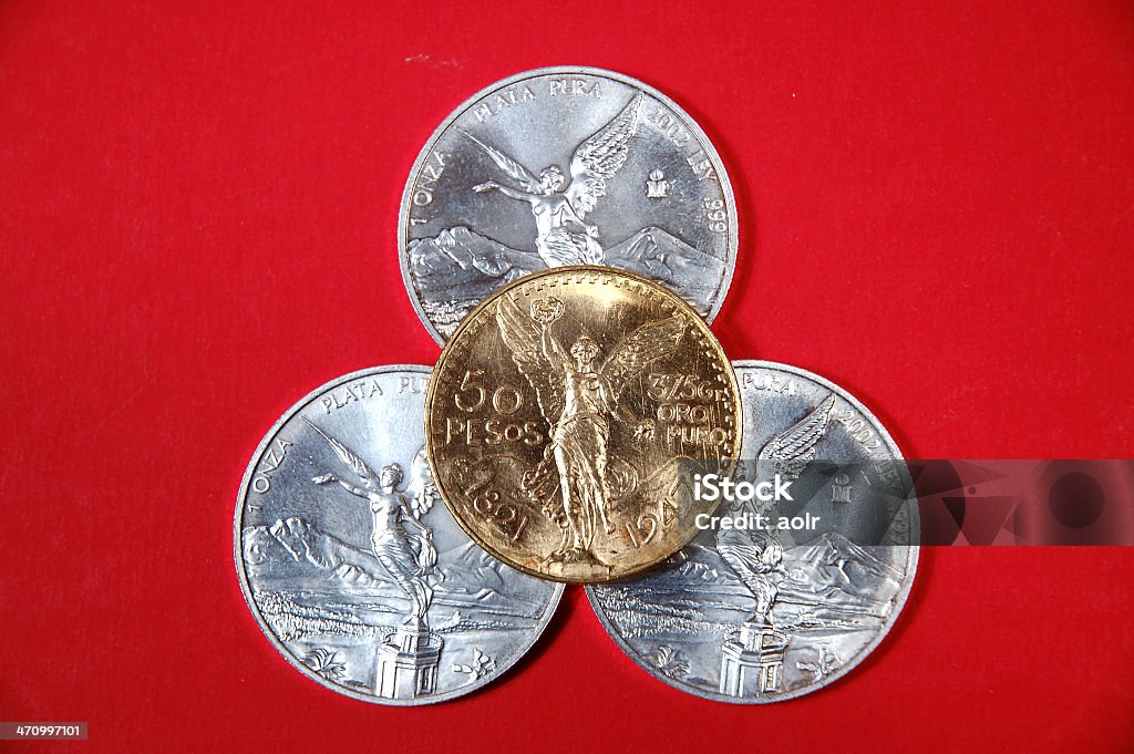 Gold over silver Three one ounce silver coins with one  one ounce gold coin on the top. Angel Stock Photo
