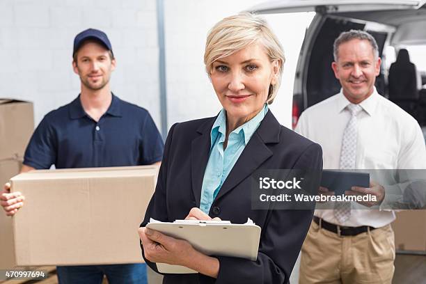 Smiling Manager Holding Clipboard In Front Of His Colleagues Stock Photo - Download Image Now