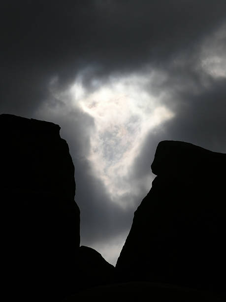 dramatic rocks against clouds stock photo