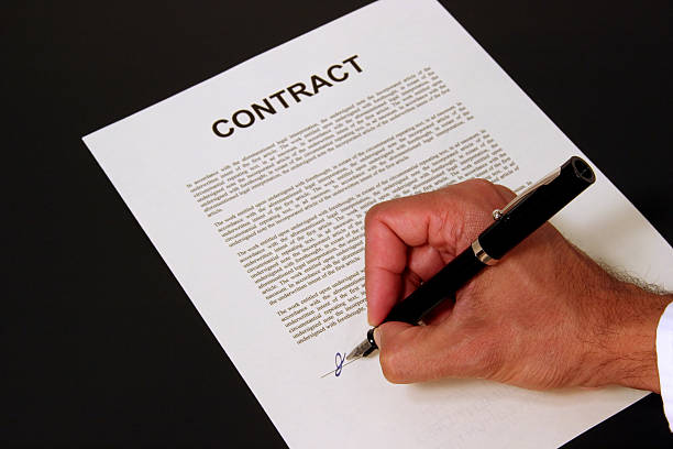 A man's hand signs a document labelled \