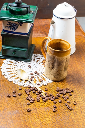 Coffee still life. Coffee grinder, coffee beans, jug and spoon on wooden table. Studio shot