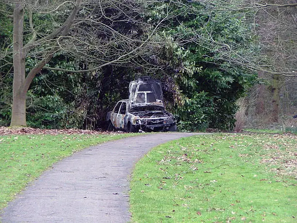Photo of an abandoned car in Wythenshawe, Manchester, England, UK. The car was likely stolen locally before being dumped here in a local park, where it was then set on fire. The park wardens removed it later the same day.