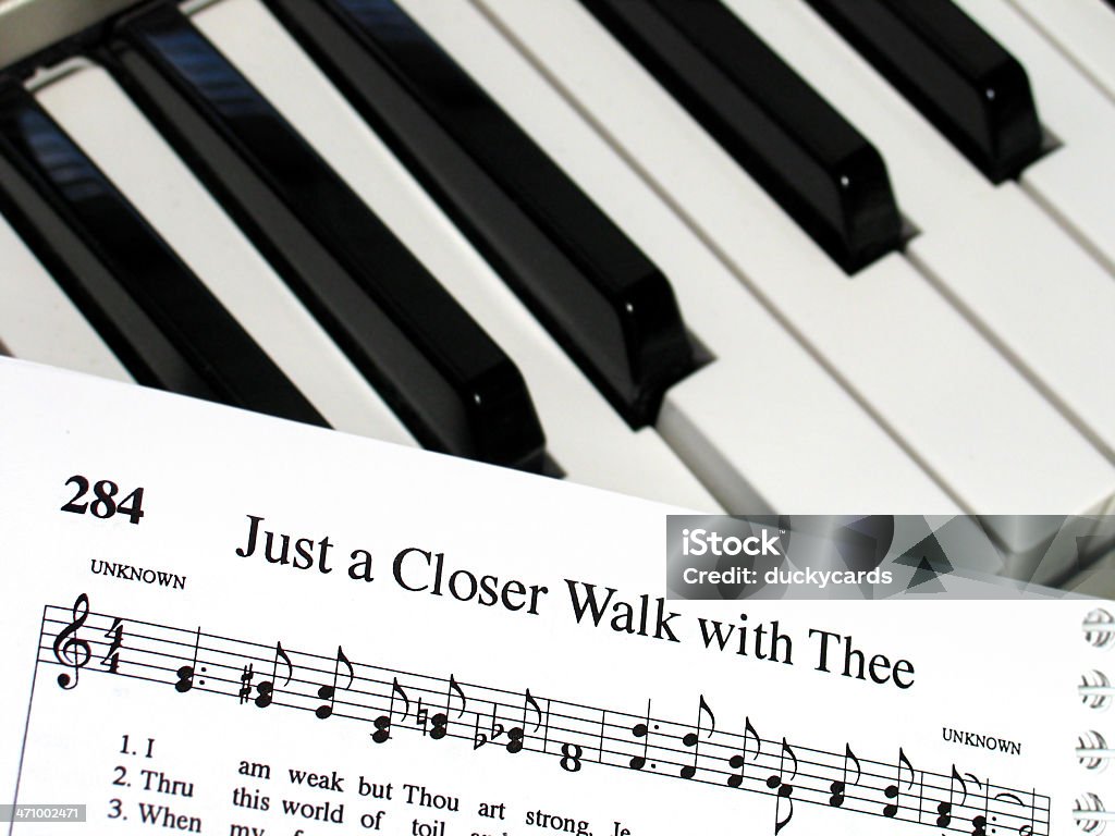 Piano Hymns A spiral hymn book open to "Just a Closer Walk with Thee" on a digital piano keyboard. Music Stock Photo