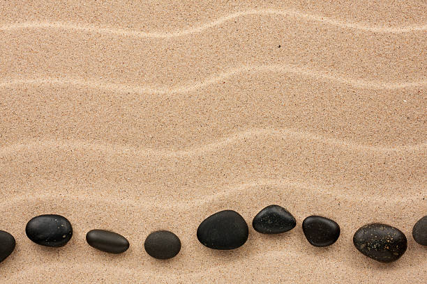 istock Black stones lie on the sand 471005610