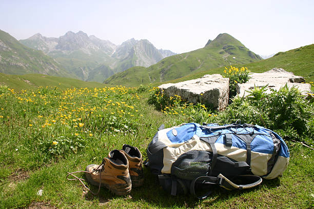 A back pack and walking boots laying in a meadow of yellow flowers in fron of a mountain scene above Lech in Austria.