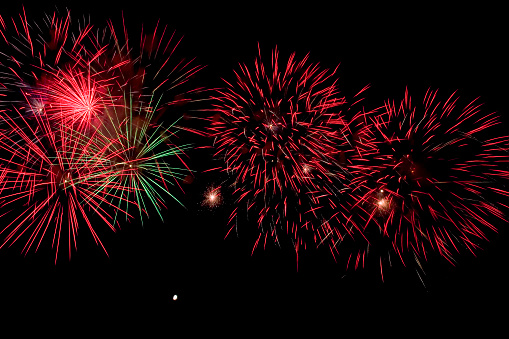 Red and green fireworks isolated black sky and tiny moon