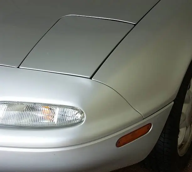 Headlight and front fender detail of a Mazda Miata.