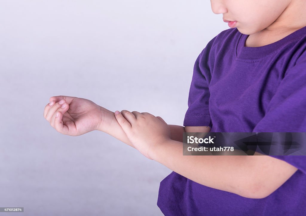 A young boy in a purple shirt checking his pulse Boys checking his arm with muscle pain. Child Stock Photo