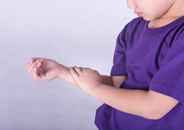 Photo of A young boy in a purple shirt checking his pulse