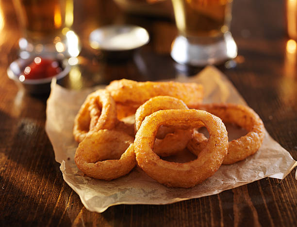 golden onion rings with beer in the background - lökring bildbanksfoton och bilder