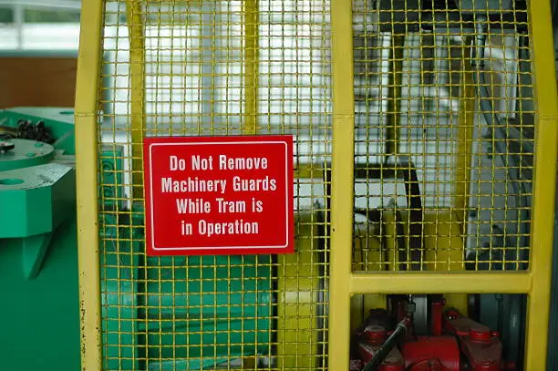 A warning sign saying "Do not remove machine guards while tram is in operation".