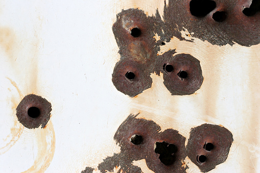 bullet holes rusting on white steel, macro with copyspace.