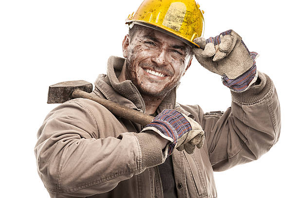 Young dirty Worker Man With Hard Hat helmet  holding a hammer and smiling isolated on White Background