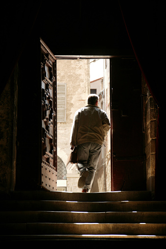 man leaving old building into bright sunshine