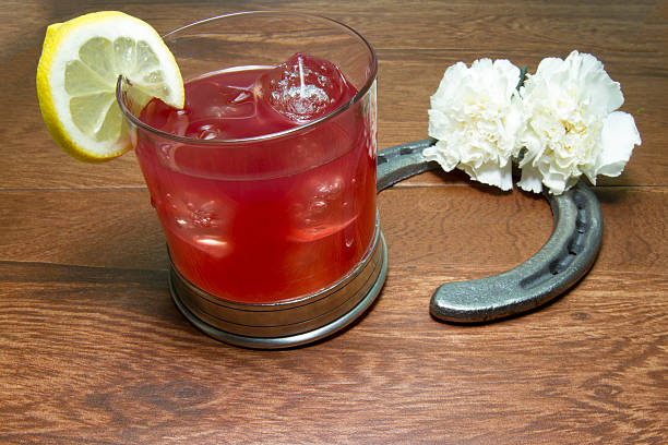 Belmont Jewel cocktail, official drink of the Belmont Stakes, with the official flower white carnations and a cast iron horseshoe on wood planks