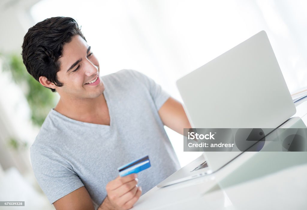 Man shopping online from home Young man shopping online from home with a credit card Financial Bill Stock Photo