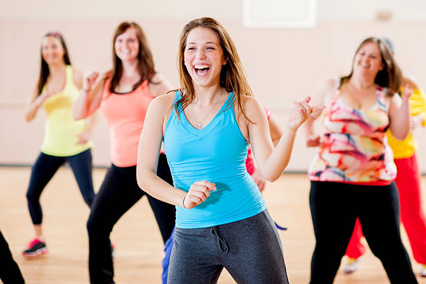 Female Class A group of young adult women in a fitness class, happy and laughing while dancing in the studio. zumba image stock pictures, royalty-free photos & images
