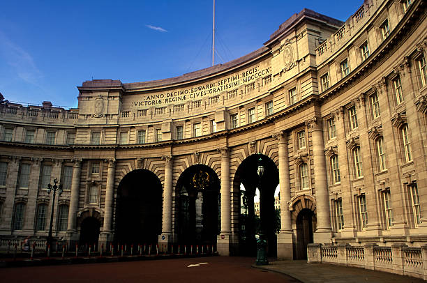 Admiralty Arch is a large office building in London which incorporates an archway providing road and pedestrian access between The Mall, which extends to the southwest, and Trafalgar Square to its northeast. The building was commissioned by King Edward VII in memory of his mother Queen Victoria, although he did not live to see its completion. A Latin inscription along the top reads \\\
