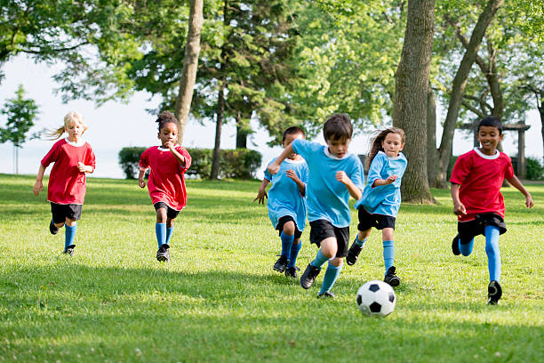 Chasing the Soccer Ball Multi-ethnic group of kids playing soccer together at the park. children only stock pictures, royalty-free photos & images