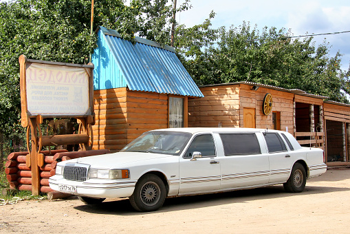 Yaroslavl region, Russia - August 26, 2011: White limousine Lincoln Town Car parked near the wooden buildings.
