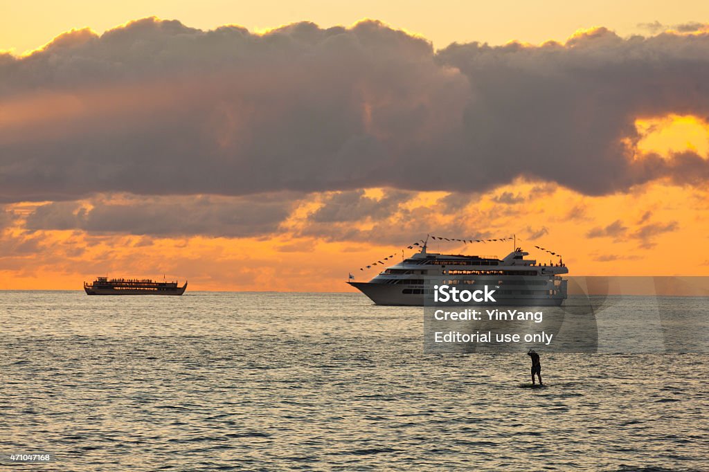 Cruise Ship Tour Boat in Waikiki Beach, Honolulu, Hawaii Honolulu Oahu, Hawaii, USA - Jan 11, 2015: The sunset over the famous tourist destination of Waikiki Beach with sightseeing tour boats and a paddle-boarder. Cruise - Vacation Stock Photo