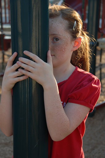 A young red-haired, all-American girl peers from around a pole...our kids are 