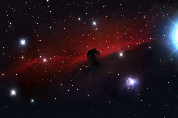 The Horsehead Nebula (also known as Barnard 33 in bright nebula IC 434) is a dark nebula in the Orion constellation. The nebula is located just below Alnitak, the left star of Orion's Belt. It is approximately 1,500 light years from Earth,and is approximately 3.5 light years wide.One of the most identifiable nebulae in the sky, it is part of a swirling cloud of dark dust and gases,shaped like a horse's head.The red glow originates from hydrogen gas predominantly behind the nebula, ionized by the nearby bright star Sigma Orionis. The darkness of the Horsehead is caused mostly by thick dust, although the lower part of the Horsehead's neck casts a shadow to the left. Streams of gas leaving the nebula are funneled by a strong magnetic field. Bright spots in the Horsehead Nebula's base are young stars just in the process of forming.