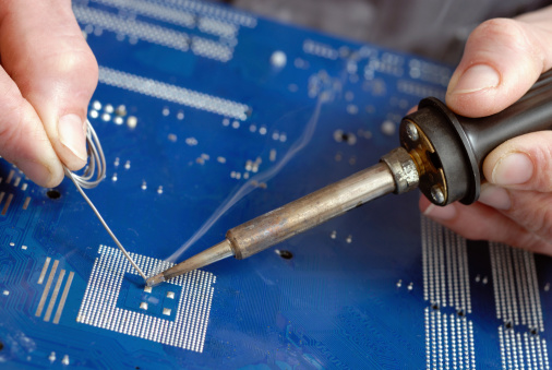 Soldering a circuit board ,focus on the cone end of the soldering iron, smoke flag clearly visible.