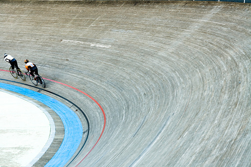 bicycle racers flying around curve in bicycle racing velodrome, slight motion blur
