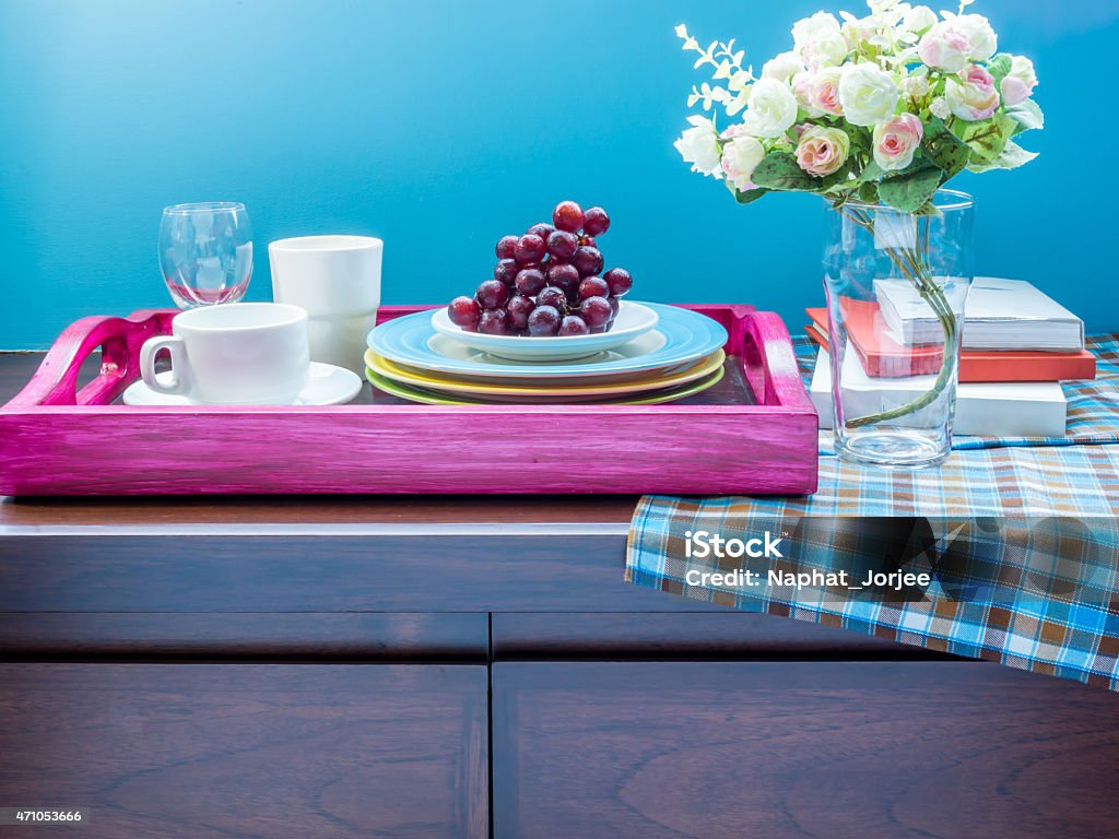 Flower vase, tea cup, dishware in wooden tray/ interior still-life Flower vase, tea cup, dishware in wooden tray on wooden cupboard/ interior still-life 2015 Stock Photo