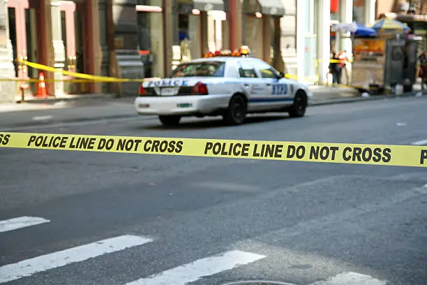 Police tape hangs across a street in front of a building, New York City, New York, USA.