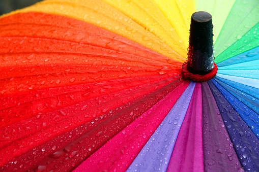 A rainbow umbrella covered in rain.