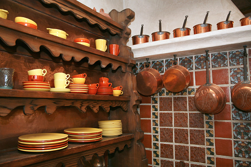 Tableware on kitchen cabinet and copper pots and pans hanging from shelf, Scotty's Castle, Death Valley National Park, California.