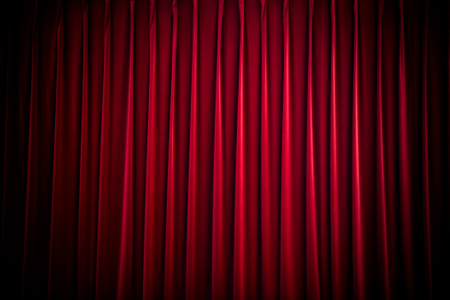 deep red stage curtain in spotlight, background texture with space for text