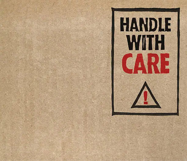 "Handle with care" on brown cardboard.