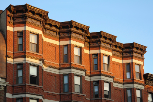   A row of historic townhouses in Hoboken, New Jersey just catching the late day setting sun. The repeating horizontal architectural bands on the facade add additional impact to the striking ornamental details found above the top set of windows. (See more in my \