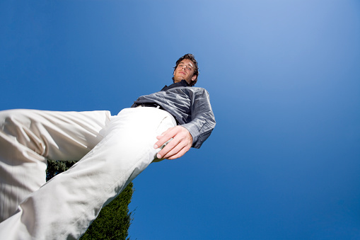 young man walking in summer park, looking down, shot from below, copyspace for your text.