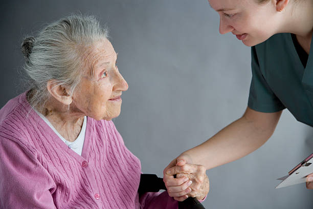 Old lady holding the hand of her nurse stock photo