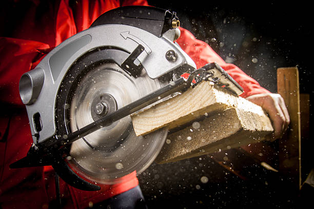 Carpenter with Circular Saw Close-up of carpenter cutting a wooden plank sawhorse stock pictures, royalty-free photos & images