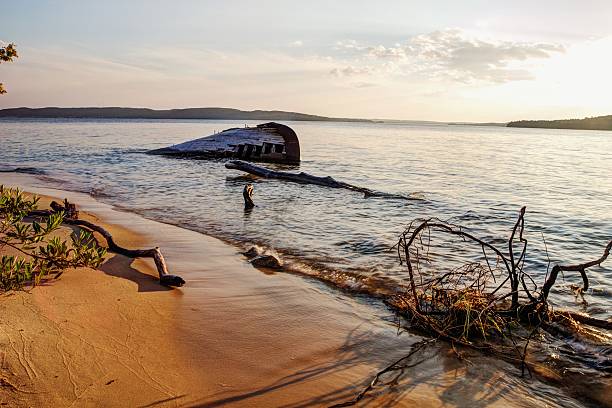 Lake Superior Coast With Shipwreck Background Shipwreck beached on the shores of Lake Superior. The southern shores of this inland sea are known as the "Graveyard Coast" and have caused the demise of many vessels. This was shot near the town of Munising, Michigan and is located in the National Park of Pictured Rocks. ghost ship stock pictures, royalty-free photos & images