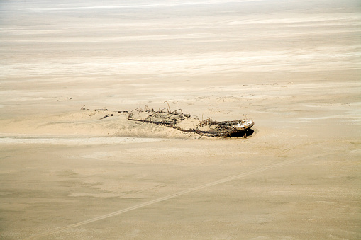 Shipwreck covered from sand dunes in the desert, surreal scenery. Aerial View down the Skeleton Coast Desert, Nambia, South West Africa.